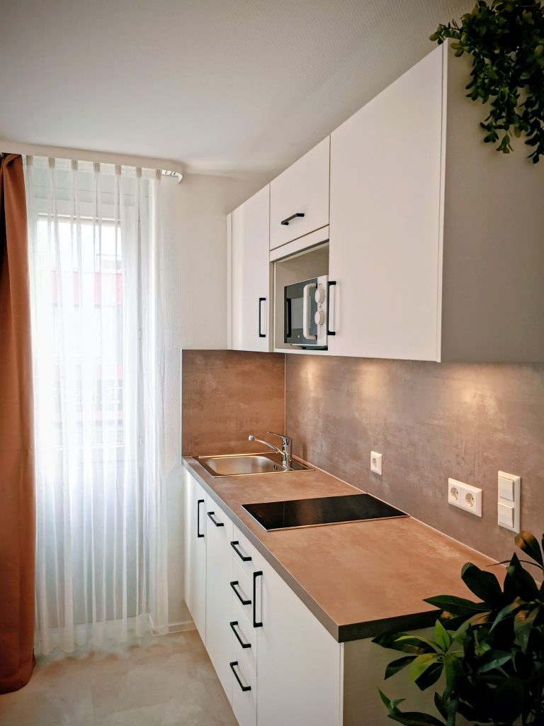 Helle Küchenzeile mit Kochfeld, Spüle und Mikrowelle in Apartment 18